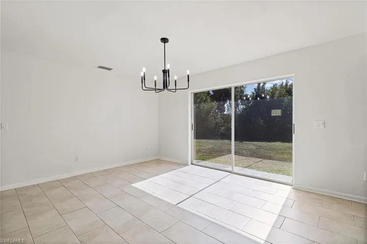 Spare room with a chandelier and light tile patterned floors