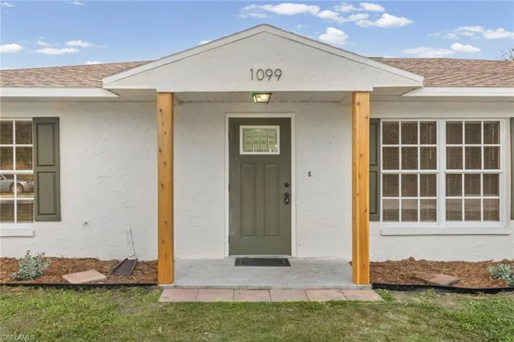 Entrance to property featuring a shingled roof and stucco siding