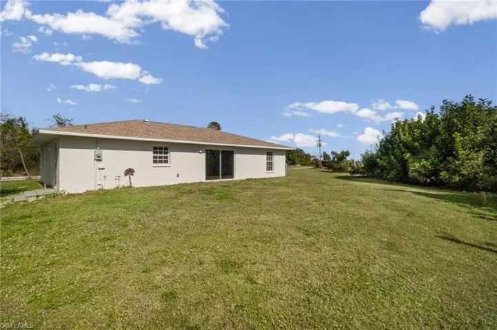 Back of property with a yard and stucco siding