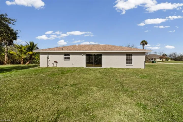 Back of property with a yard and stucco siding
