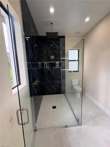 Bathroom with a marble finish shower, tile patterned floors, and recessed lighting