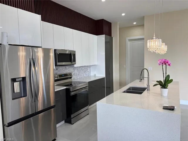 Kitchen featuring appliances with stainless steel finishes, modern cabinets, white cabinetry, light stone countertops, and recessed lighting
