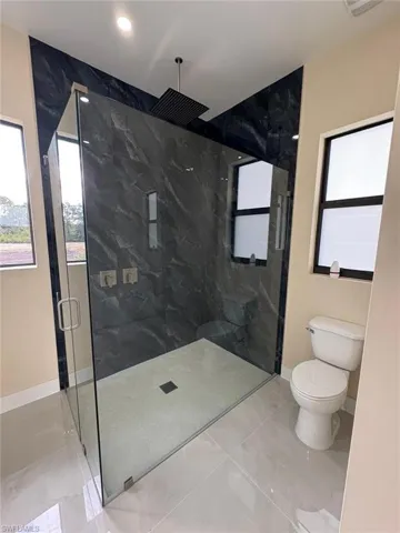Bathroom with a marble finish shower and tile patterned flooring