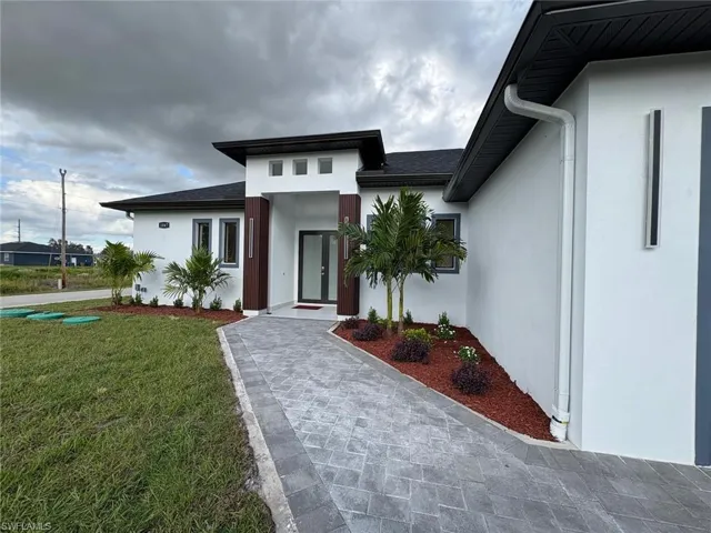View of front of property featuring a front lawn, stucco siding, and roof with shingles