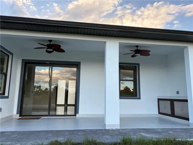 View of exterior entry featuring ceiling fan, stucco siding, and a patio area