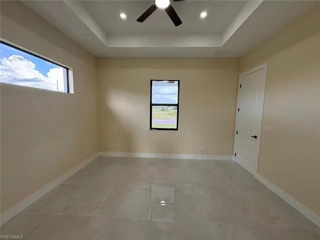 Spare room featuring a tray ceiling, ceiling fan, recessed lighting, and light tile patterned floors