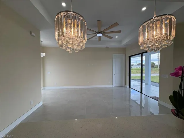 Unfurnished dining area with a chandelier, ceiling fan, recessed lighting, and a tray ceiling