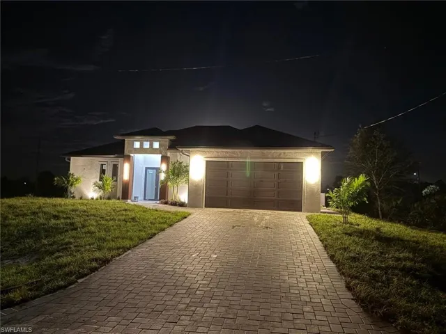 View of front facade featuring decorative driveway, stucco siding, a garage, and a lawn