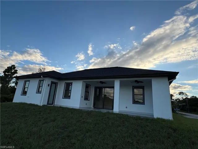 Back of property with ceiling fan, stucco siding, and a yard