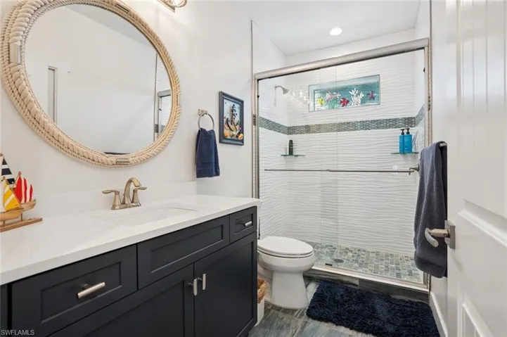 1st Bathroom featuring a tiled stall shower, glass sliding doors, toilet, and vanity