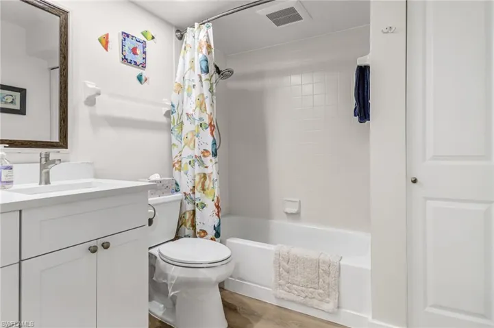Full bathroom featuring shower / tub combo, wood-type flooring, toilet, and vanity with extensive cabinet space
