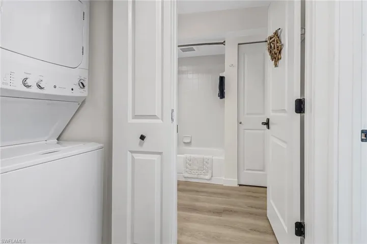 Laundry room featuring stacked washer / drying machine and light hardwood / wood-style floors
