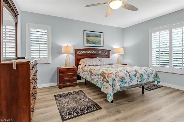 Bedroom with ceiling fan, multiple windows, and light hardwood / wood-style flooring