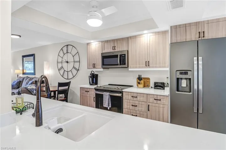 Kitchen with stainless steel appliances, sink, light brown cabinetry, and ceiling fan