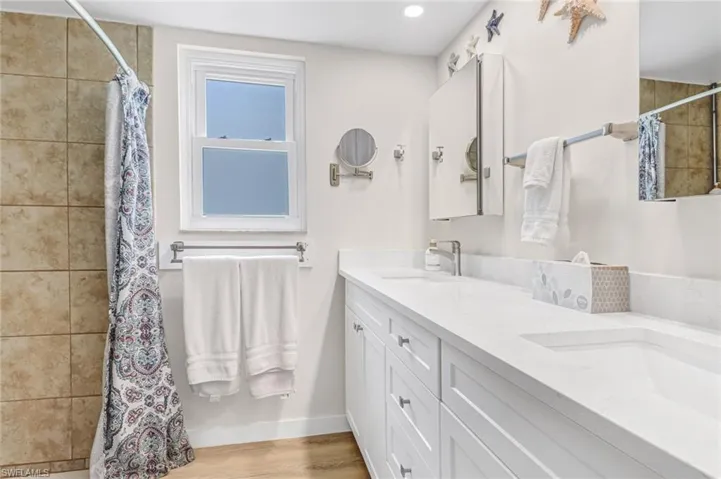Bathroom with dual vanity and hardwood / wood-style floors