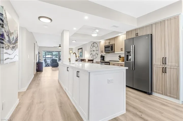 Kitchen featuring ceiling fan, stainless steel appliances, light hardwood / wood-style flooring, and a center island with sink