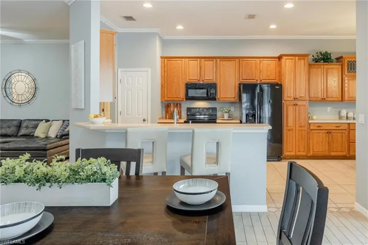 Kitchen with a breakfast bar, black appliances, pantry cupboard along with abundance of cabinets. The cabinet pantry has pull-out drawers.