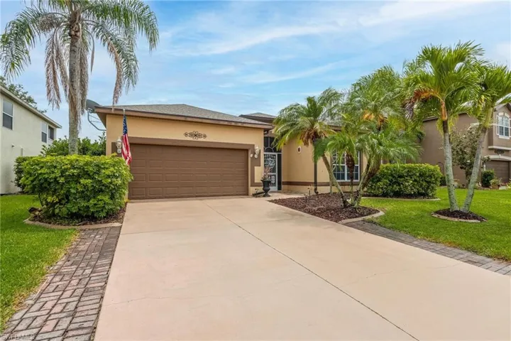 View of front of home featuring 2 car garage, mature landscaping, Long driveway.