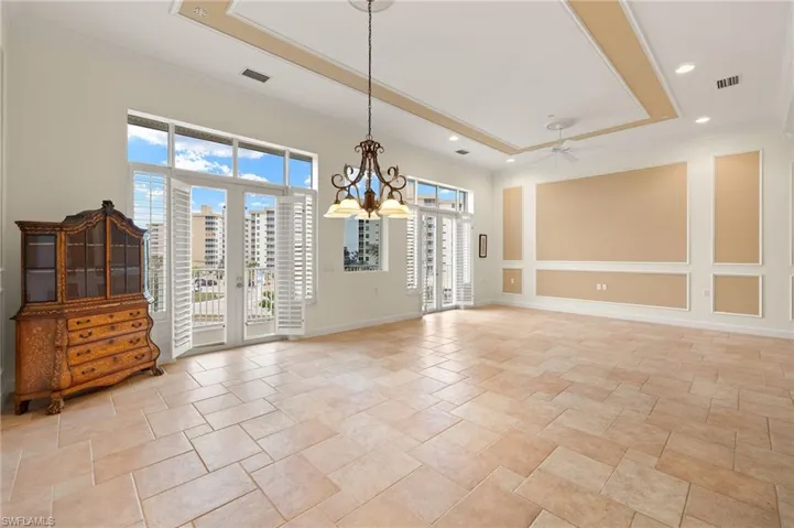 Dining  area with crown molding, ceiling fan with notable chandelier, and a raised ceiling