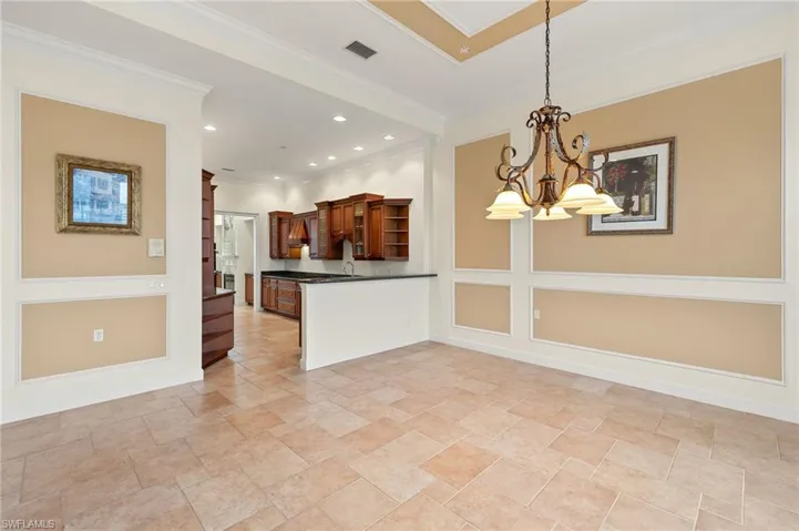 Kitchen featuring kitchen peninsula, pendant lighting, crown molding, and a chandelier