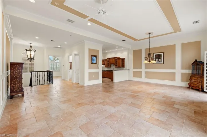 Living room featuring a tray ceiling, ceiling fan with notable chandelier, and ornamental molding