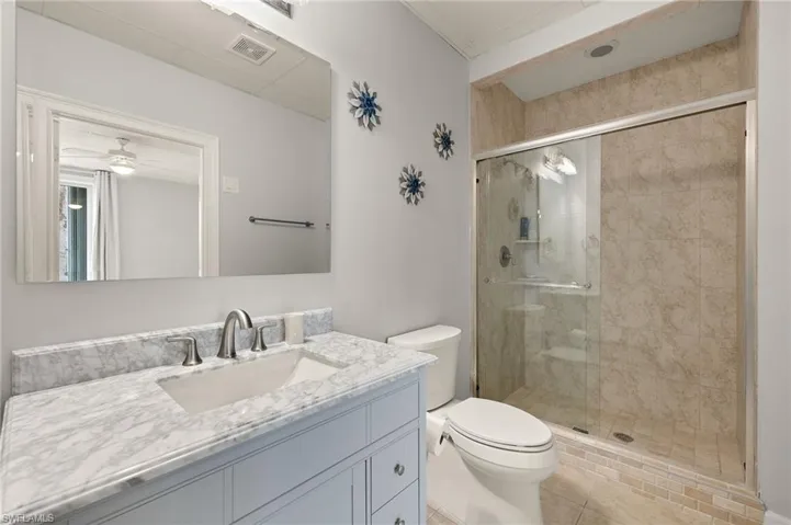 3rd Full Bathroom with a shower with shower door, vanity, ceiling fan, and toilet