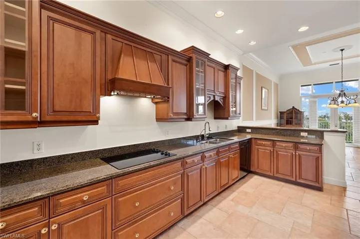 Kitchen featuring pendant lighting, black appliances, custom exhaust hood, an inviting chandelier, and sink
