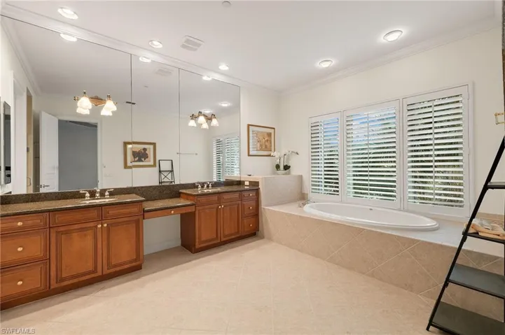 Master Bathroom with ornamental molding, tile patterned flooring, tiled tub, and vanity