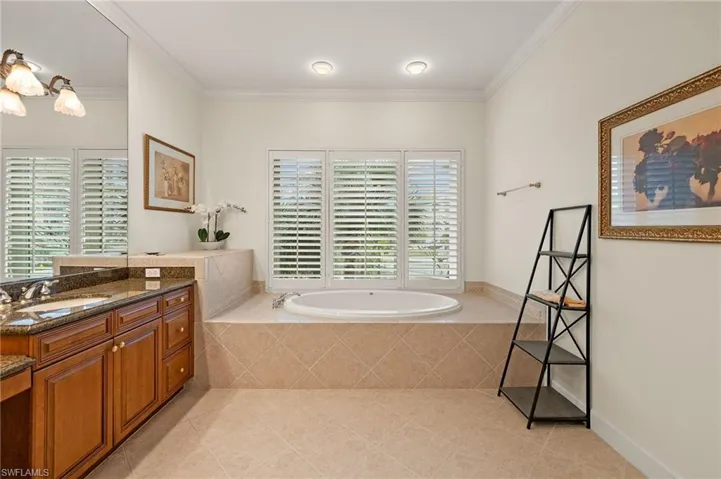 Master Bathroom featuring tiled bath, crown molding, tile patterned floors, and vanity