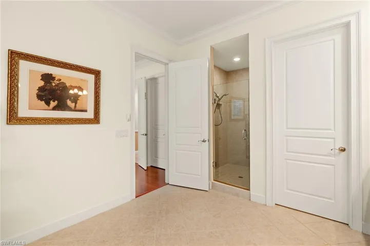 Master Bathroom with shower, light tile patterned flooring and ornamental molding