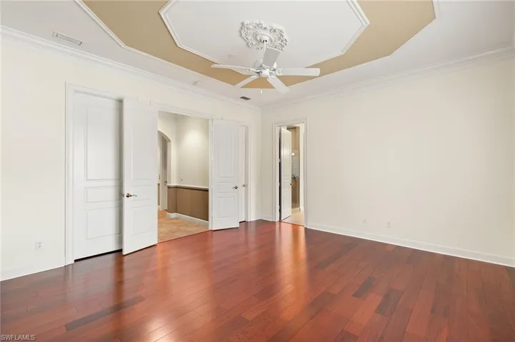 Master bedroom featuring ceiling fan, a tray ceiling, ornamental molding, and hardwood / wood floors