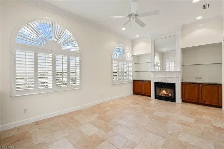 Den featuring fireplace,  built in shelves, plenty of natural light, a premium fireplace, and ornamental molding