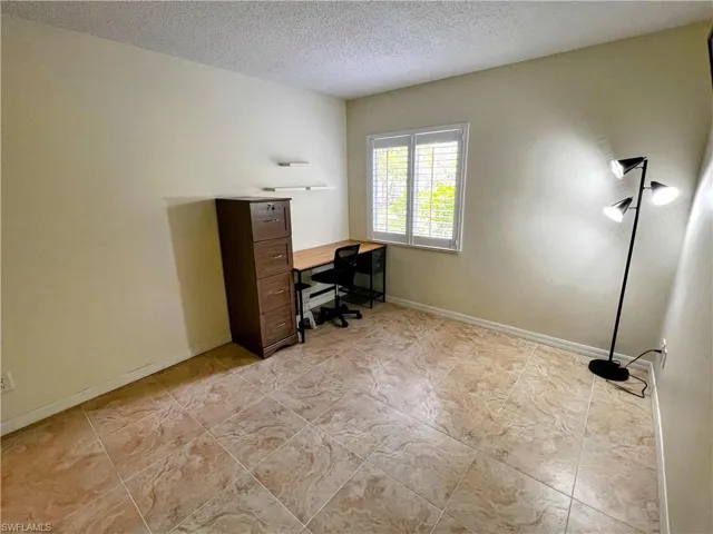 Office space featuring light tile patterned floors, a textured ceiling, and baseboards
