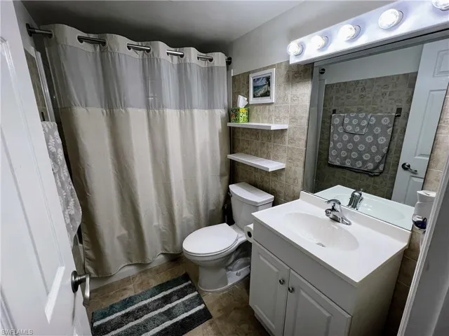 Full bath with tile walls, shower / tub combo, toilet, and vanity