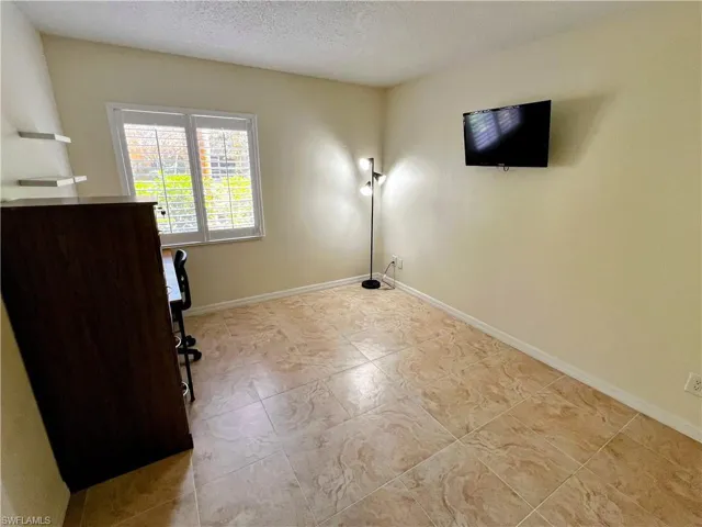 Unfurnished office with a textured ceiling and baseboards