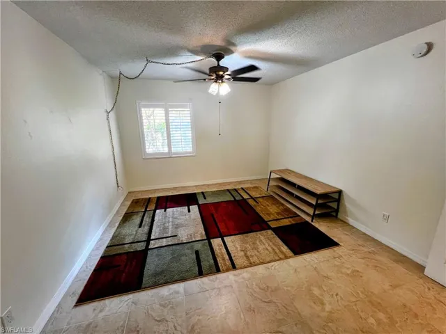 Spare room featuring a ceiling fan, a textured ceiling, and baseboards
