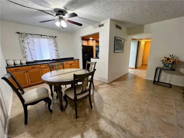 Dining room featuring a textured ceiling, visible vents, and ceiling fan