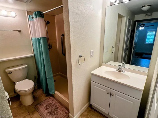 Full bath featuring tile patterned floors, a shower stall, toilet, vanity, and visible vents