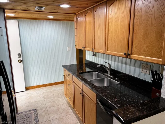 Kitchen featuring recessed lighting, a sink, wooden ceiling, black dishwasher, and dark stone countertops