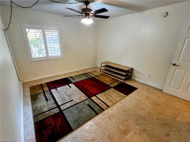 Unfurnished bedroom with a ceiling fan and a textured ceiling