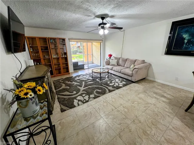 Living area with baseboards, ceiling fan, and a textured ceiling