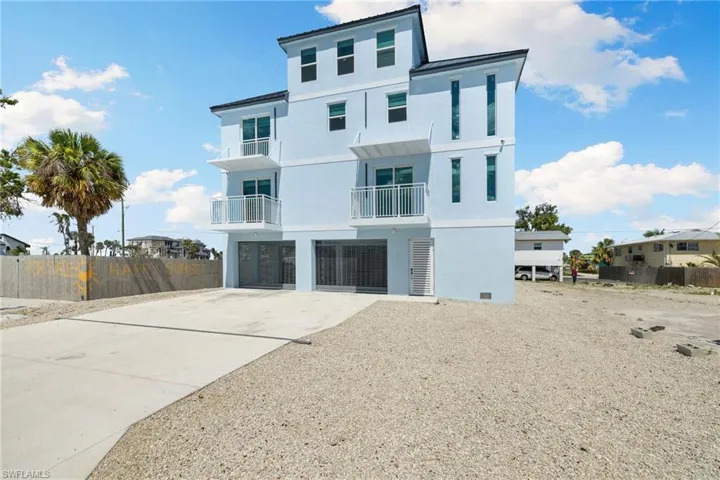 View of front of house with driveway, stucco siding, and fence