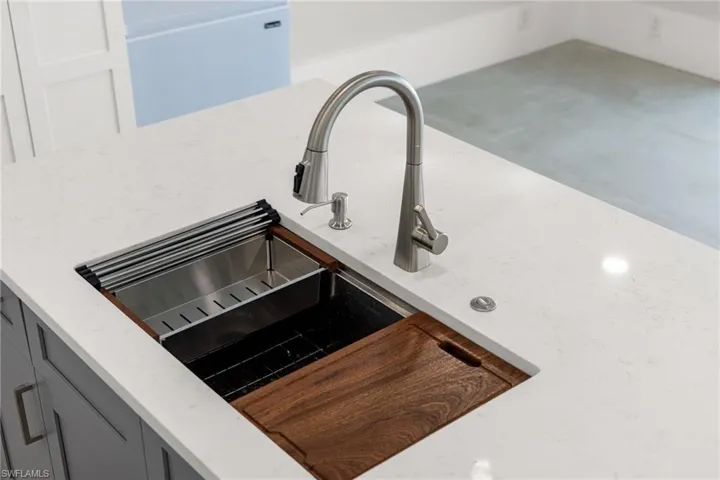Room details with gray cabinets, light stone counters, and a sink