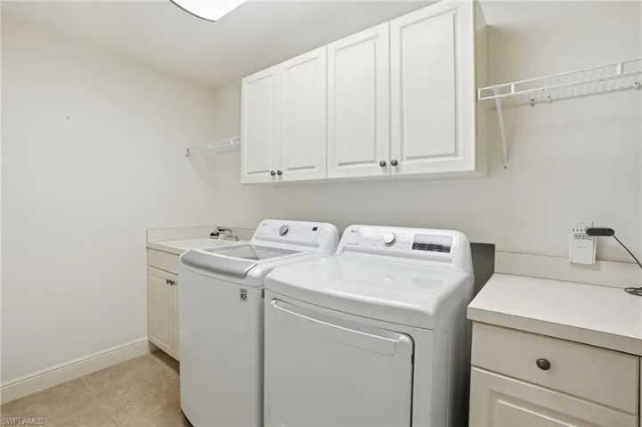 Laundry room featuring separate washer and dryer, cabinet space, and light tile patterned flooring