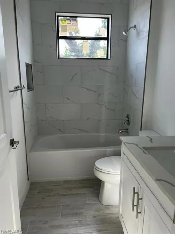 Full bathroom featuring tub / shower combination, vanity, and wood tiled floors