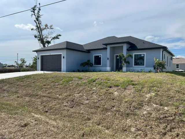 View of front facade featuring an attached garage, a front lawn, concrete driveway, and roof with shingles