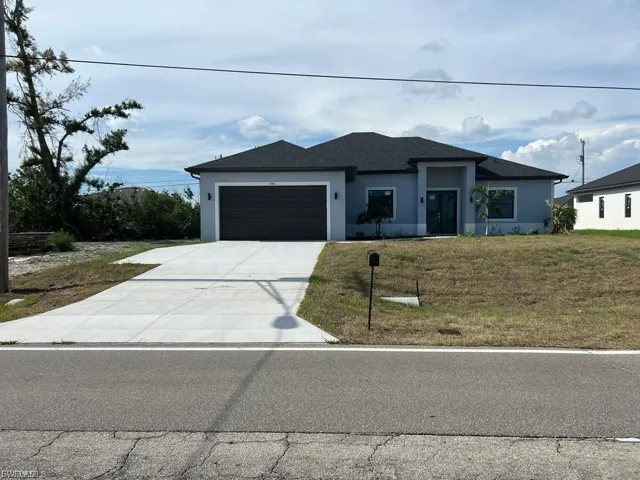 Prairie-style home with a front yard, concrete driveway, a garage, and roof with shingles