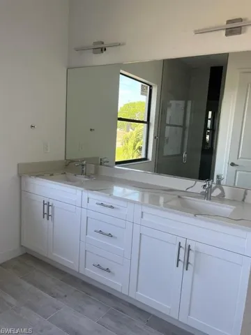 Full bath with double vanity and wood finish floors