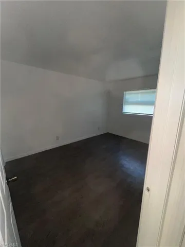Additional living space with dark wood finished floors and baseboards