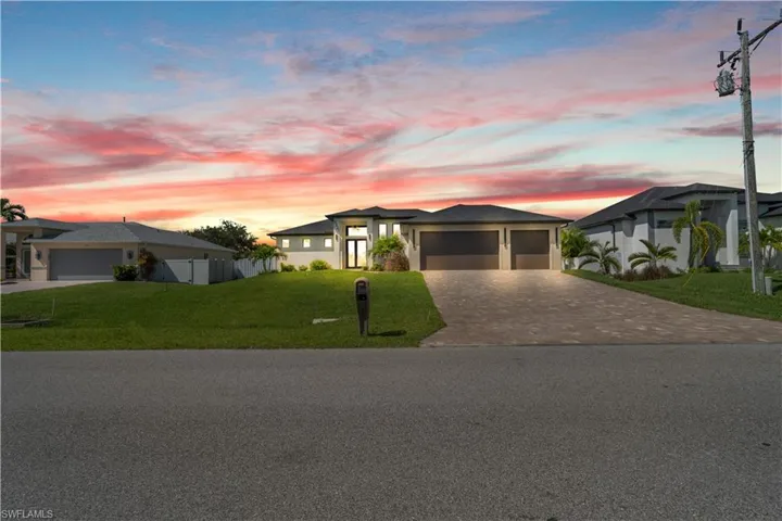 Contemporary-style residence featuring a paved driveway, two-car garage, and a lush green lawn